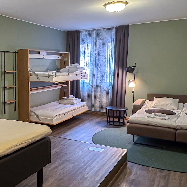 Familjerum Large med en stor bäddsoffa för två personer, två väggmonterade bäddar och en dubbelsäng. Rummet är rymligt och rymmer upp till sex personer.