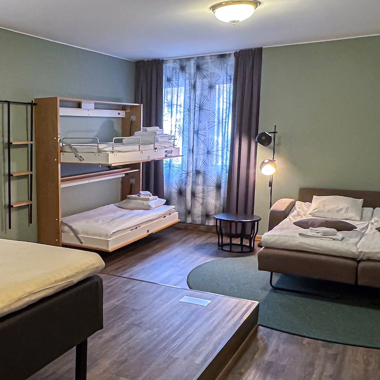 Familjerum Large med en stor bäddsoffa för två personer, två väggmonterade bäddar och en dubbelsäng. Rummet är rymligt och rymmer upp till sex personer.