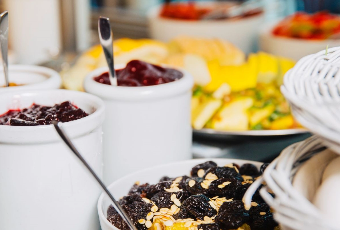 Granola och mûslitopping på ett frukostbuffébord. Här syns frukt, torkad frukt och sylt och bärkompott.