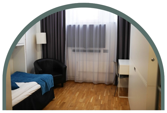 Bilden visar ett ekonomirum cabin på Kom Hotel i Stockholm. Rummet har trägolv och ett fönster, 2 våningssängar med totalt 4 bäddar. Fönstret ramas in av gardiner. 