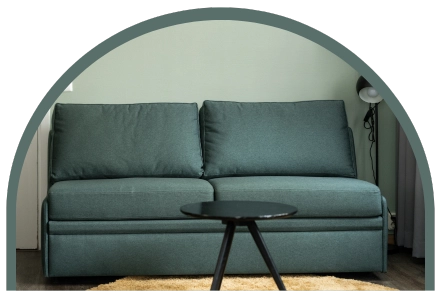 En bäddsoffa i dova gröna färger med ett bord framför