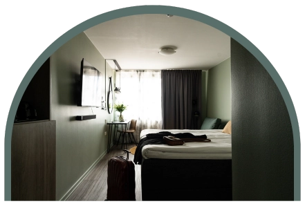 Ett hotellrum med en dubbelsäng, TV och en resväska ståendes framför sängen.