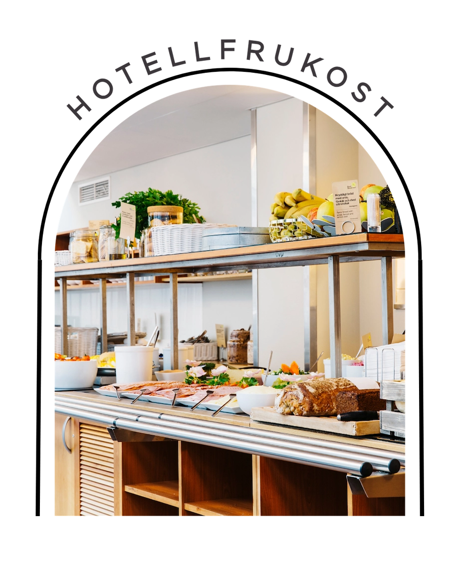 Frukostbuffébord i trä på Kom Hotel. Bordet är överfyllt av en uppdukad frukostbuffé med grönsaker, frukt och pålägg till smörgåsar.
