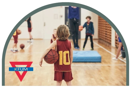 Bilden visar ett barn som står med ryggen vänd mot kameran i en idrottshall, under armen har han en basketboll. Detta symboliserar Kfums ägandeskap av Kom Hotel. Överskottet från hotellet går tillbaka till barn- och ungdomsverksamhet.