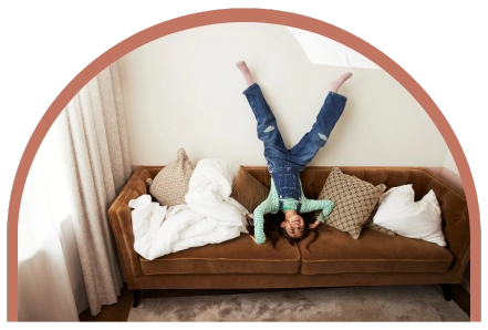 Flicka som står på huvudet i en soffa på ett hotellrum
