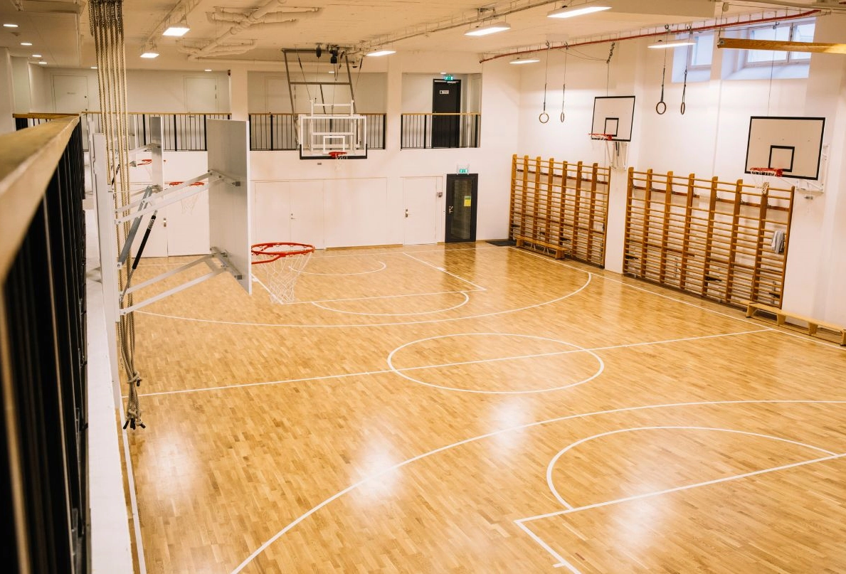 Det här är idrottshallen på Kom Hotel. Den är stor och rymlig och i bild syns 4 basketkorgar.