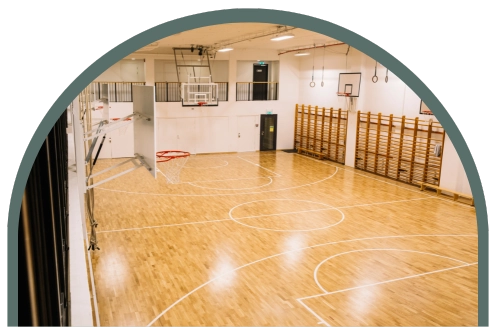Det här är idrottshallen på Kom Hotel. Den är stor och rymlig och i bild syns 4 basketkorgar.